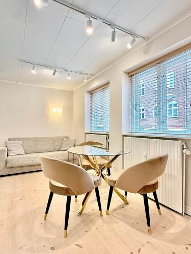 a living room with a glass table and two chairs at Det Gamle Vaskeri - Historical Apartment in Horsens in Horsens