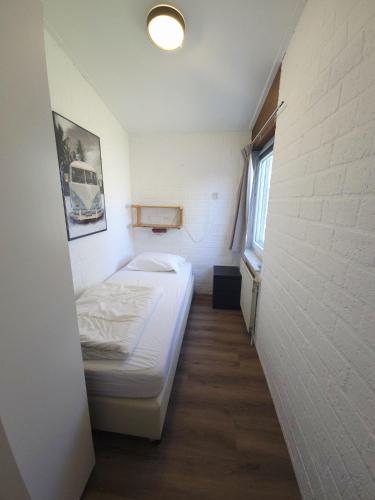 a small room with a bed and a white wall at De Blenck 69 in Callantsoog