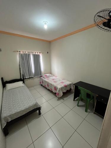 a room with two beds and a table and a desk at Casa no pavimento superior in São Luís