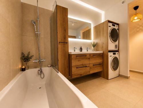 a bathroom with a tub and a sink and a washing machine at La petite maison in Mougins