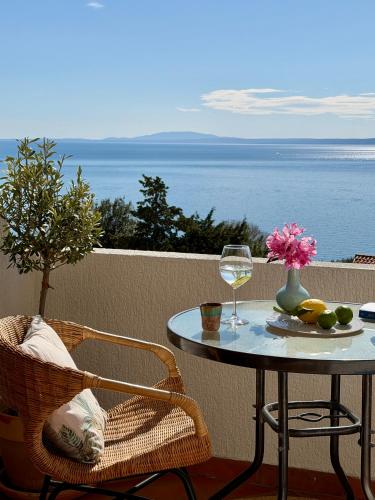 a table and chair with a glass of wine on a balcony at Sunshine Residence in Stara Baška