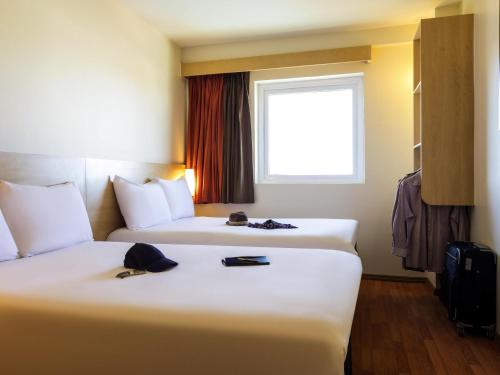 a hotel room with two beds and a window at Ibis Juarez Consulado in Ciudad Juárez