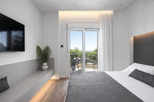 ein weißes Schlafzimmer mit Bett und Balkon in der Unterkunft The Ark in Stavros