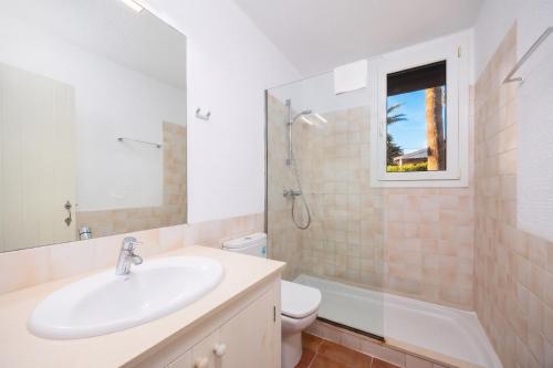 a bathroom with a sink and a toilet and a window at Villa Binipaco in Binibeca