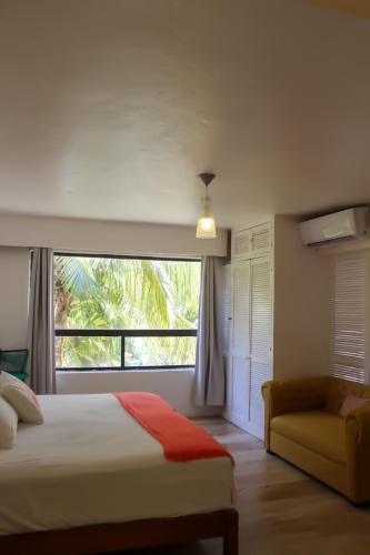 a bedroom with a bed and a window and a couch at Suites Marea in Cancún