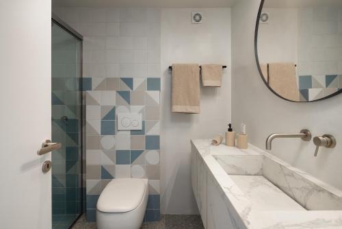 a bathroom with a sink and a toilet and a mirror at Serene Shore Serifos in Alona