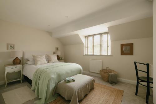 a bedroom with a bed and a chair and a window at Central Village Cottage, The Corders in Moreton in Marsh