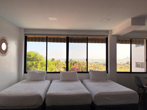 two beds in a room with large windows at Hotel La Mar Playas in Playas