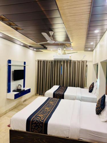 two beds in a hotel room with a tv at Hotel SK Residency in Varanasi