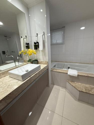 a bathroom with a sink and a bath tub at Agulhon Hotel in Primavera do Leste