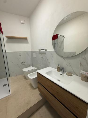 a bathroom with a sink and a mirror and a toilet at Ostello moderno centro- cucina Wi-Fi in Livorno