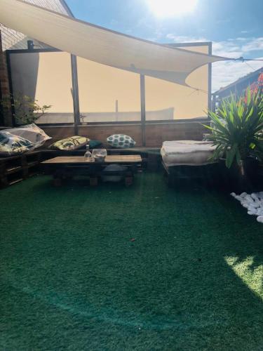a patio with grass and a couch and a table at Ático La Puerta de Logroño, con terraza y piscina! in Logroño