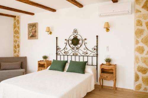a bedroom with a white bed with green pillows at La Casona del Bullaque in El Robledo