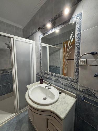 a bathroom with a sink and a shower and a mirror at La Casuca del Chiguito in Chipiona