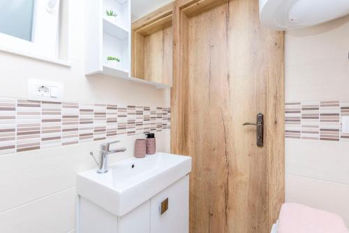 a bathroom with a white sink and a wooden door at House Romance for two in Zagvozd