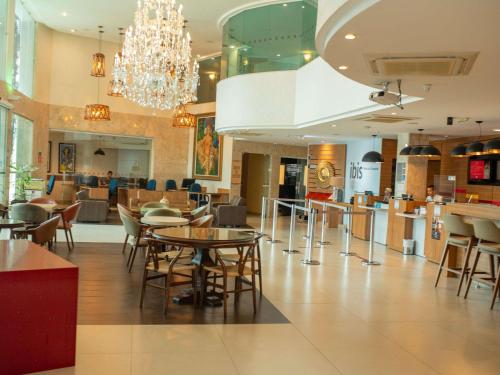 a restaurant with tables and chairs and a chandelier at ibis Vitoria da Conquista in Vitória da Conquista