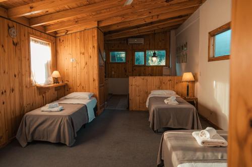 ein Zimmer mit drei Betten in einem Holzzimmer in der Unterkunft Casa 45 in San Martín de los Andes