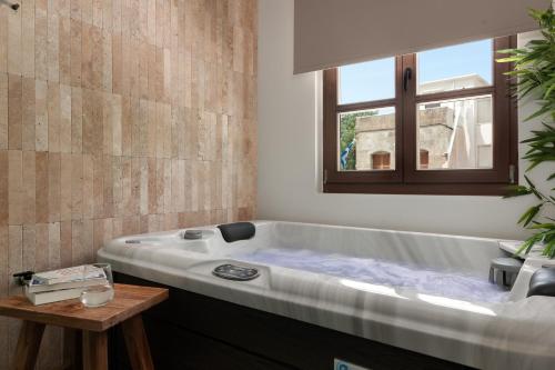 a large bath tub in a bathroom with a window at Karavel Suites - Old Town in Rhodes Town
