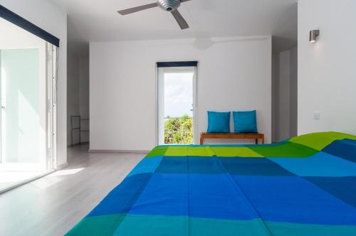 a white bedroom with a blue and green bed at Bonaire Bay View Villa in Kralendijk