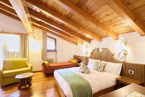 a hotel room with a bed and a chair at Hotel Beau Sejour in Etroubles