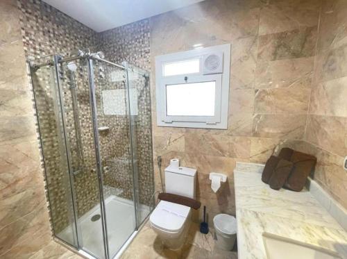a bathroom with a shower and a toilet and a window at Grand Stylish Two bedrooms Apartment in El Alamein