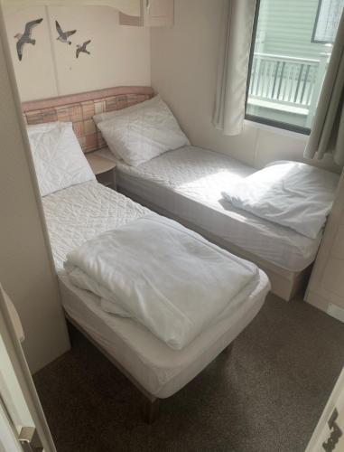 two twin beds in a room with a window at Herons mead 12 in Addlethorpe
