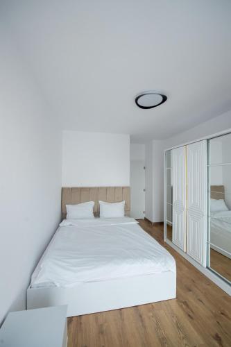 a white bedroom with a large bed and a window at Izium Central Residence in Baia Mare