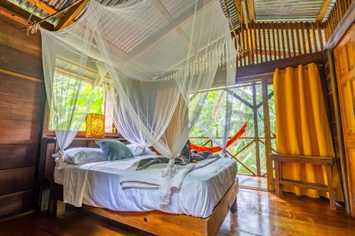 a bedroom with a bed with a mosquito net at Pure Roots in Bastimentos