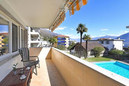 a balcony with a chair and a swimming pool at Malibu46 - Minusio Apt with Shared Pool & Balcony - Happy Rentals in Minusio
