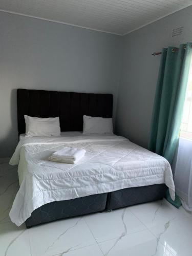 a bed with a black headboard in a bedroom at Nana Kay's apartment in Livingstone