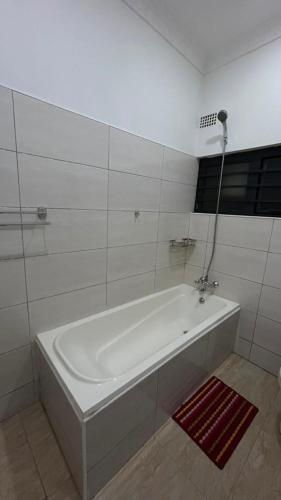 a white bath tub in a white tiled bathroom at Dk Casa in Lusaka