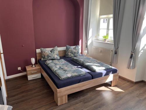 a bedroom with a bed with purple walls and a window at Ferienwohnung Goldener Hirsch in Schneeberg