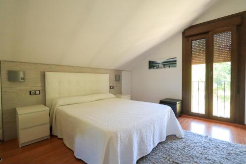 a bedroom with a white bed and a large window at Mazziu's villa in Cans