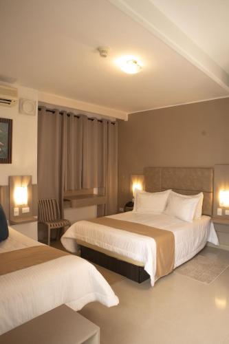 a hotel room with two beds and a chair at Los Lirios Hotel Merida in Mérida