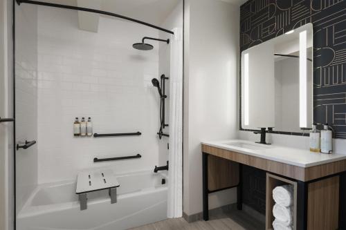 a bathroom with a tub and a sink and a mirror at Aiden Hotel Sacramento Downtown in Sacramento