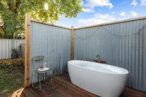 a bath tub sitting on a deck next to a fence at Queenie's Cottage in Mansfield