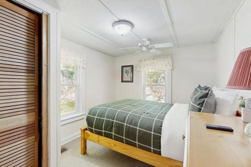 a bedroom with a bed and a desk and windows at Sebago Shores Cottage in North Sebago