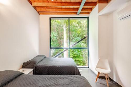 two beds in a room with a window at Beautiful private villa with an ecological pool in Santa Maria Huatulco