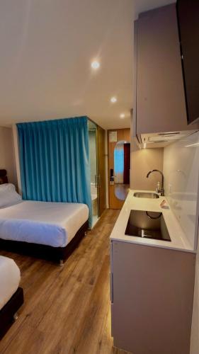 a room with two beds and a kitchen with a sink at Hotel Oliver in Bogotá