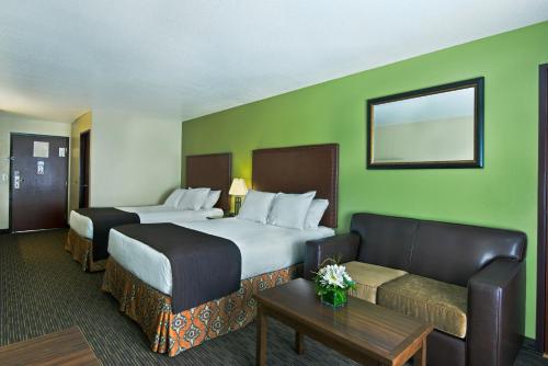a hotel room with two beds and a couch at Oxford Suites Hermiston in Hermiston