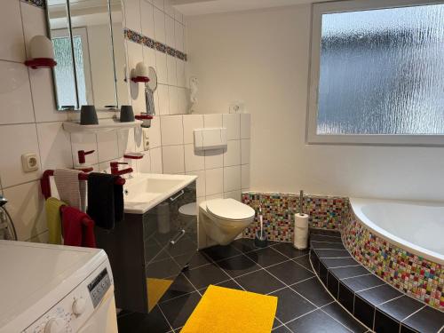 a bathroom with a tub and a toilet and a sink at Ferienwohnung Rosengarten in Osburg