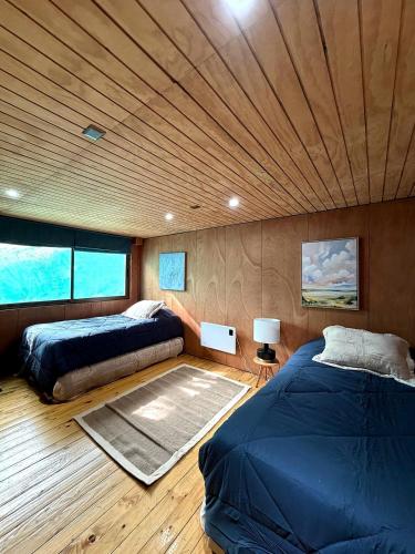 a bedroom with two beds and a wooden ceiling at Santuario Lodge Arrayan in Lo Barnechea
