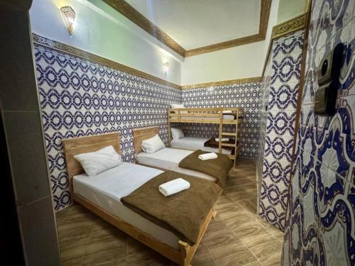 two beds in a room with blue and white wallpaper at Riad Al Anwar in Rabat