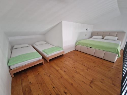 two beds in a small room with wooden floors at Blue Horizon Rezevici in Katun