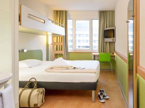 a hotel room with a bed and a desk at ibis budget Zurich Airport in Glattbrugg