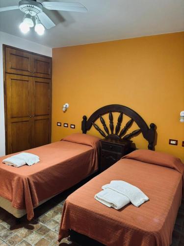 two beds in a room with yellow walls at Hotel las ruedas by Choca in Arroyito