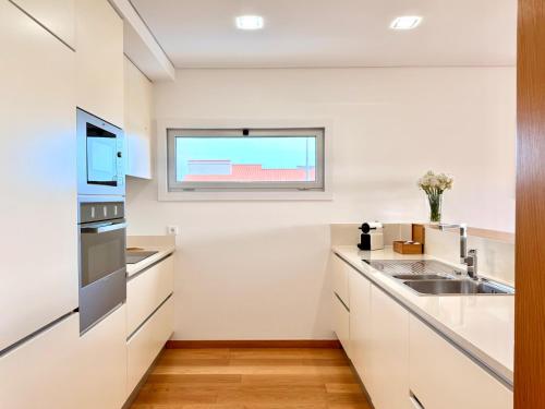 a kitchen with white cabinets and a window at T2 Dunas Esposende in Esposende