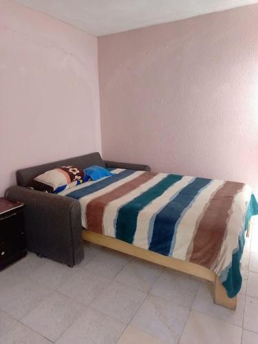 a bedroom with a bed with a striped blanket on it at House near AIFA in San Cristóbal