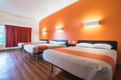 three beds in a room with an orange wall at Motel 6-Globe, AZ in Globe