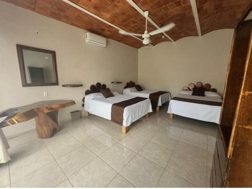 a room with two beds and a table in it at Hotel El Texcalame in Lo de Marcos